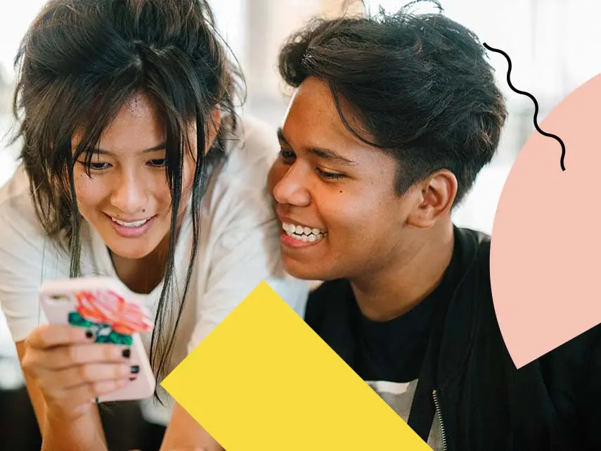 Två unga personer som tittar i en mobil och skrattar