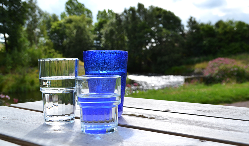 Tre vattenglas med vatten i står på ett bord utomhus.