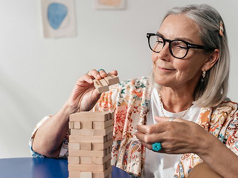 Äldre kvinna bygger ett torn av stavar.